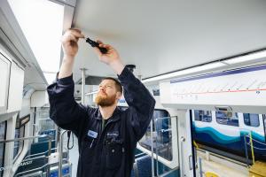 A maintenance crew member installs new LED lights on a Link light rail train