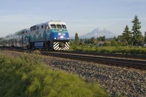 A Sounder train rolls through fields with Mt. Rainier in the background