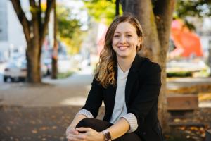 Sound Transit employee Ariel Taylor smiles while sitting outside in a park.