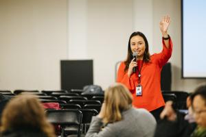 Jackie Martinez-Vasquez raises her hand while speaking at a community event.