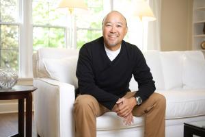 Sound Transit employee Alan Yamamoto smiles while sitting on a couch.