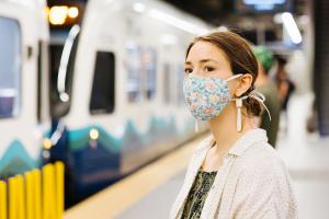 OMFS Oct 2020 Project update header image, photo of woman wearing a mask at a train station