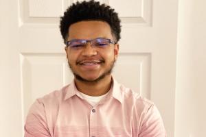 Christopher Adams smiles at the camera, wearing a button-down shirt and glasses.