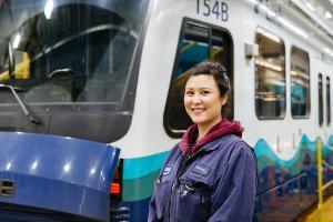 Sound Transit employee stands in front of Link light rail train at an operations and maintenance facility