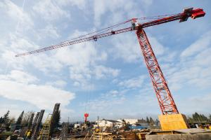 Looking up at a large red crane and a blue sky with scattered clouds behind it.