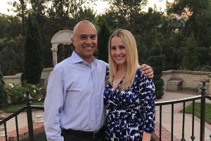 Jennifer Lemus and her husband Rudy smile for a photo, with green trees in the background.