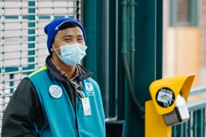 Marlon Herrera smiles at the camera while wearing a blue beanie, teal vest and blue face mask.