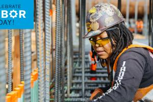 A woman works on rebar. A tag on the top left reads 'Happy Labor Day.'