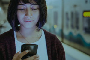 A rider looks at her phone while waiting on the platform 