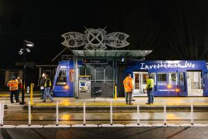 A blue T Line train pulls into a new station at nighttime. 