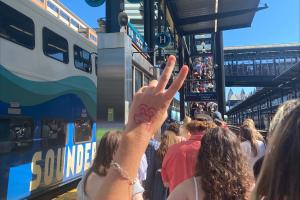 A hand with the number 13 drawn on it is held up in front of a Sounder train