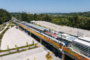 Link trains at the South Bellevue Station on a sunny day, with trees and downtown Bellevue in the background