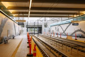 The platforms and tracks at the Spring District light rail station, with black painted aluminum artwork on the walls