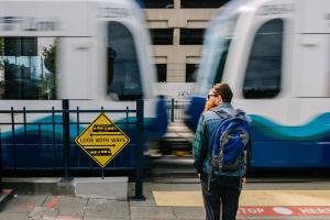 A person with a backpack stands at a safe distance away from a passing train