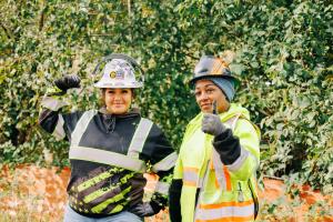 Cicelia Thompson and Katherine Fair flex and give the thumbs up on a construction site