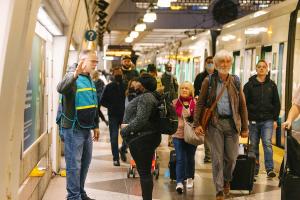 A Sound Transit staff ambassador in a teal vest helps passengers navigate a service disruption