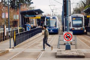 A pedestrian crossing the tracks at Columbia City Station. Note pedestrian safety improvements made by the at-grade crossing program