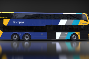 Rendering of Stride double-decker bus’s side profile. The bus exterior includes stripes as well as the Sound Transit and Stride logos. The right side of the bus has two doors for access, one at the front and one in the middle of the bus.