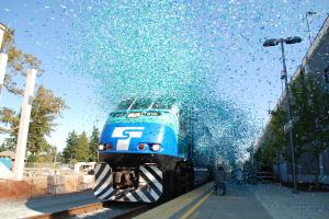 Blue and green confetti flies in front of a Sounder train