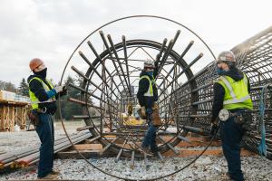 Three workers stand next to a rebar cage on the construction site in Kent Des Moines in 2021