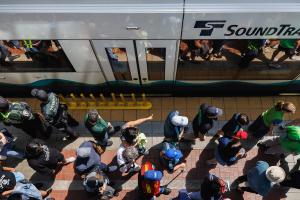 Soccer fans walk along a Link platform next to a train. The angle of the photo is shot from directly above