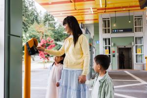 A mom holds hands with her children while tapping her ORCA card at a Link station in Bellevue on a sunny day
