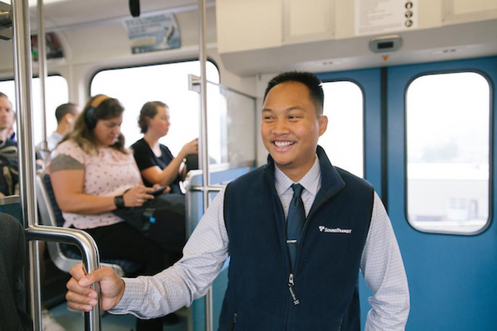 A man in a Sound Transit vest rides Link light rail.