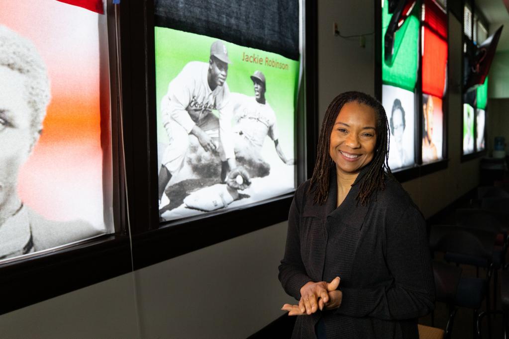 Sound Transit employee Arleen Baldwin poses in front of a photo of Jackie Robinson to honor Black History Month.