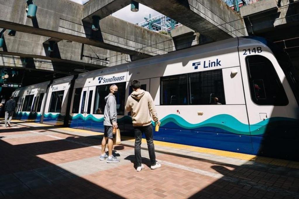 Two people stand in front of a Link train.