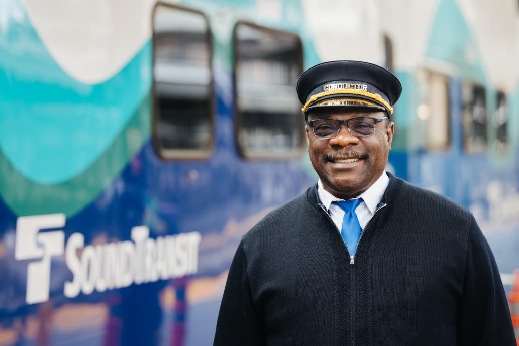 A Sounder conductor smiles outside the train.