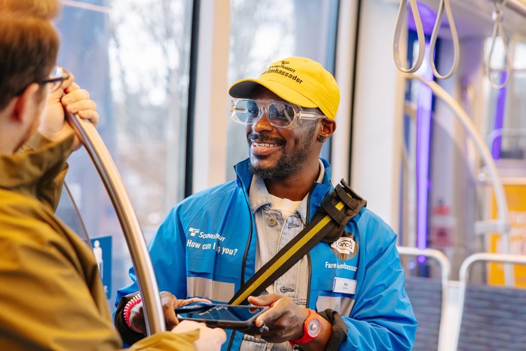 A fare ambassador speaks with a passenger on a Link light rail train.