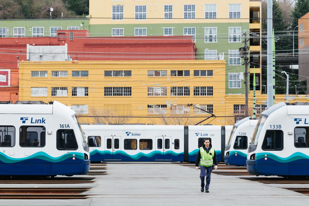 Image of person in yellow vest with light rail vehicles