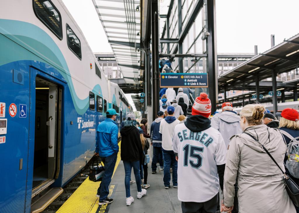 A crowd wearing Mariners gear departs a Sounder train at King Street Station.