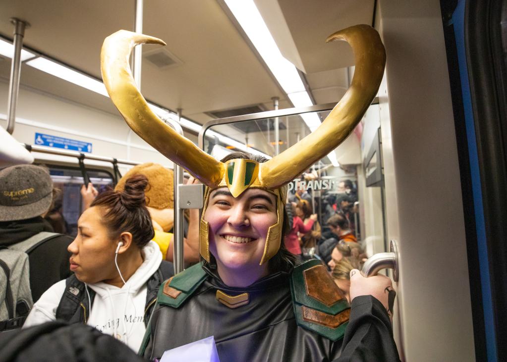 A passenger wears an ornate headpiece while riding the train to Comic Con