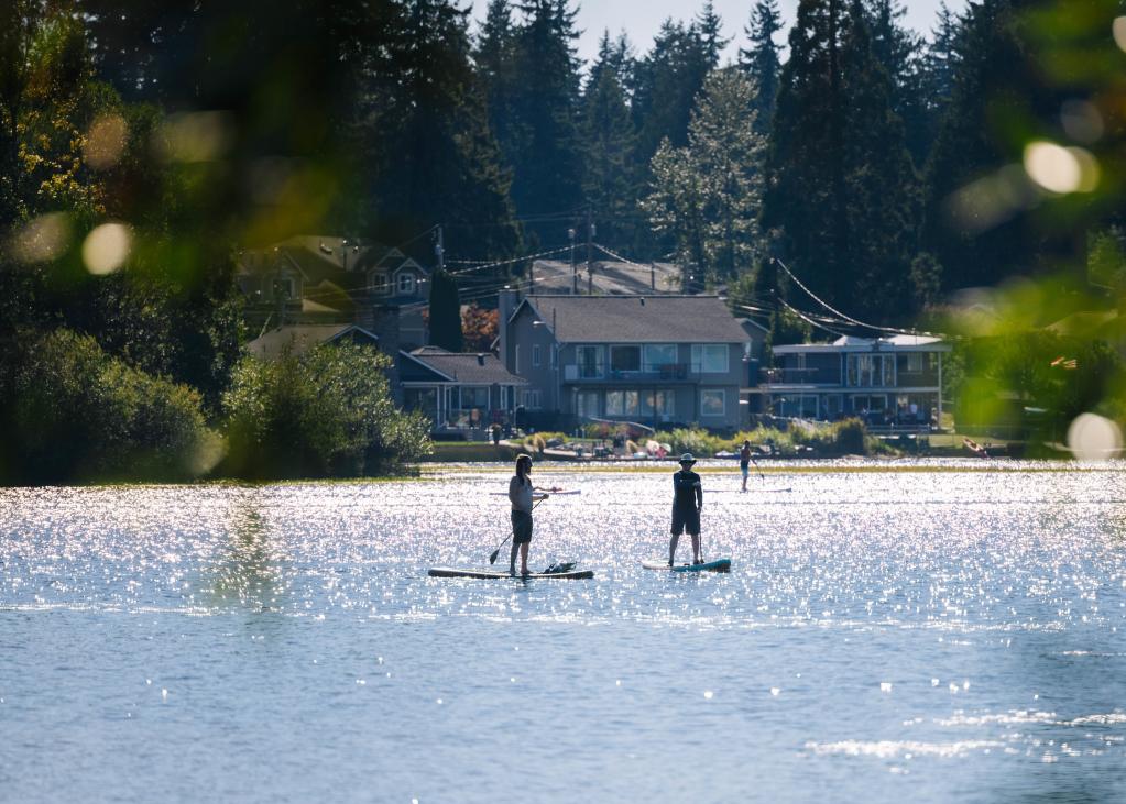 Two paddleboarders on Silver Lake as seen from the lake shore