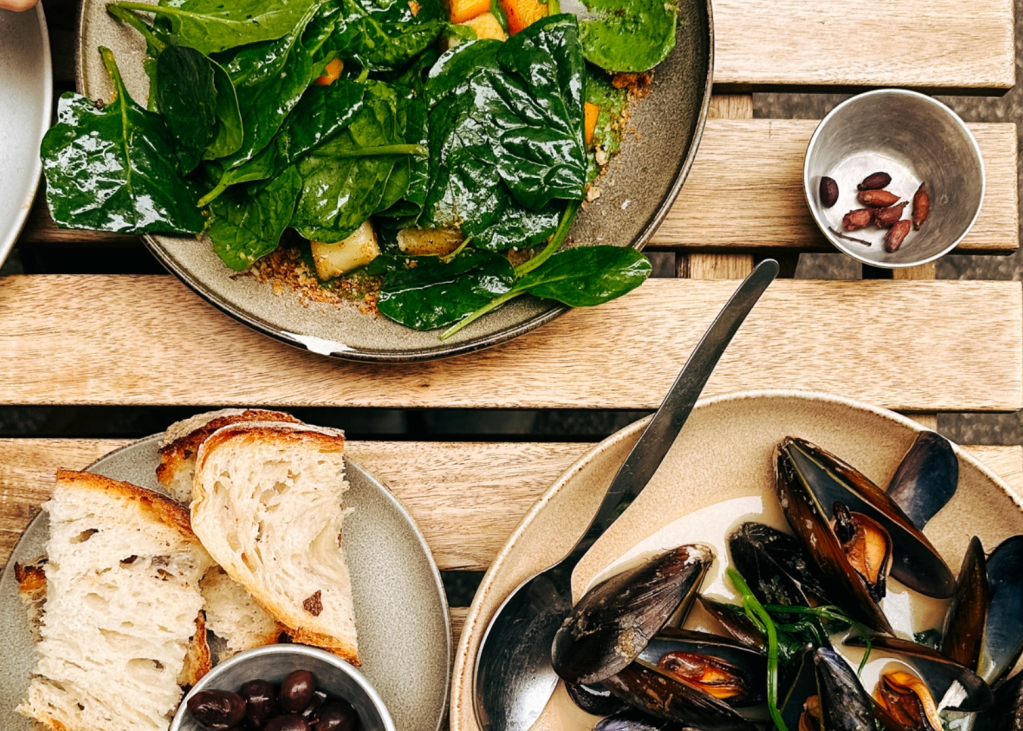 Looking down at a table with bread, mussels and salad 
