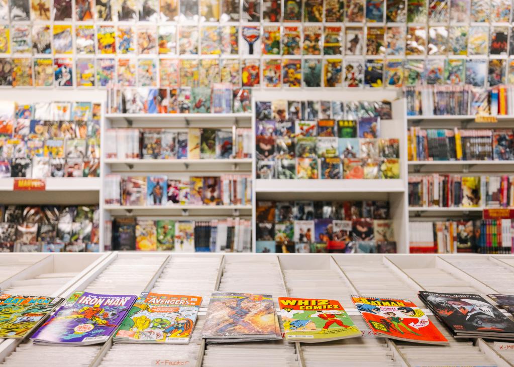 Comics line the walls of a shop, with more in boxes to browse