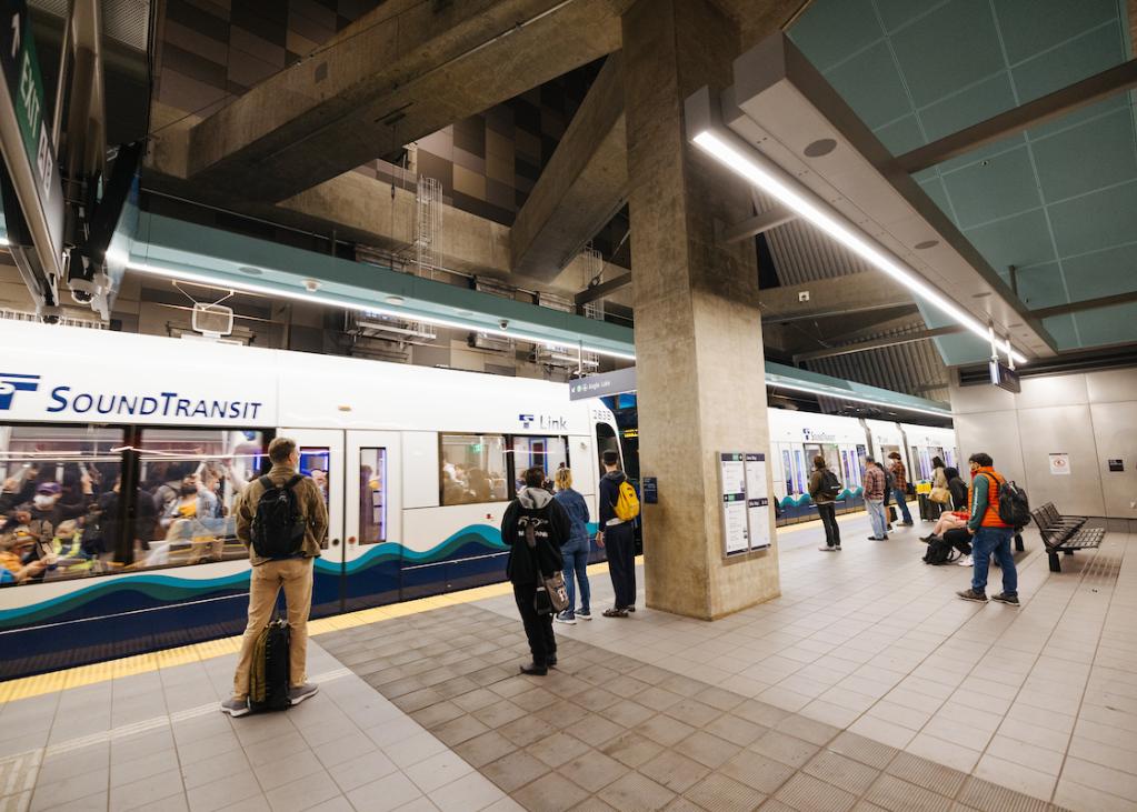 People wait on the platform at U District Station as a Link train pulls in