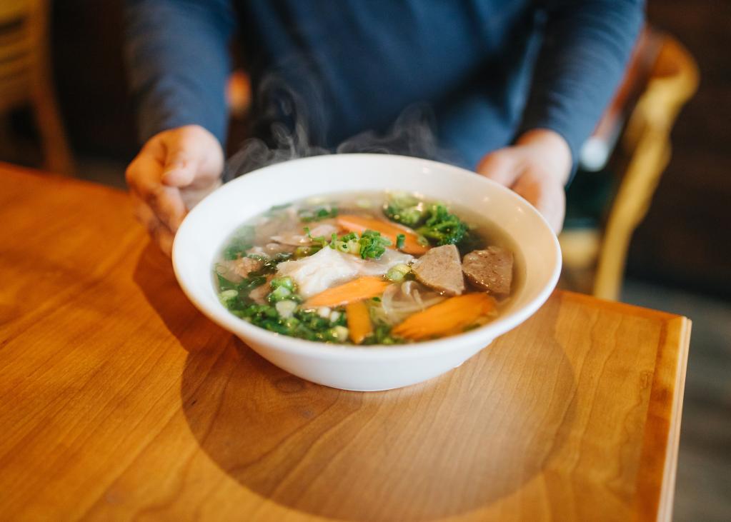 A steamy bowl of pho on a table