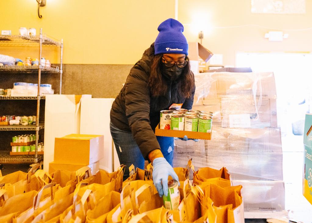 A Sound Transit employee places food in a brown bag.