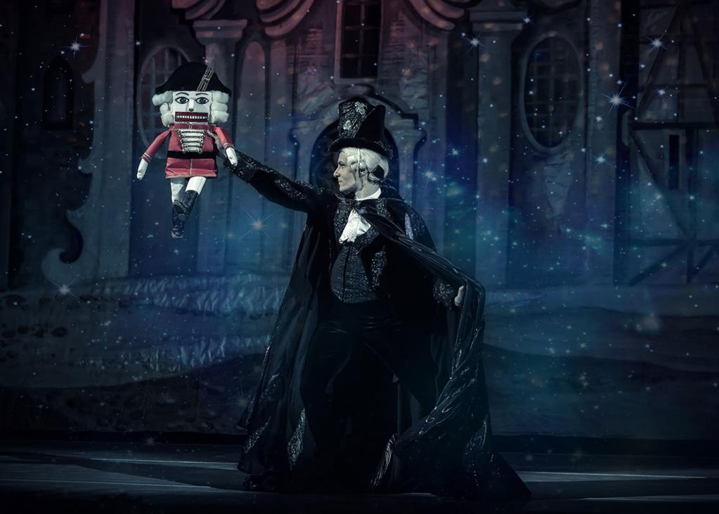 A promotional image for the nutcracker with a victorian man holding up a traditional nutcracker