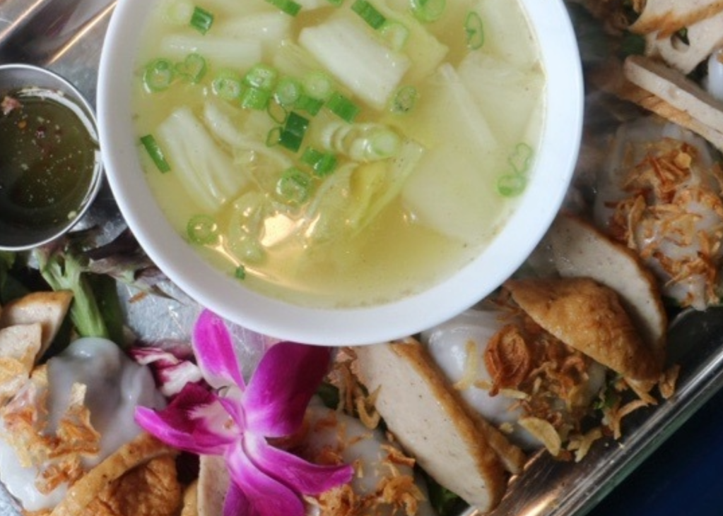A colorful plate from a Thai restaurant featuring chicken, dumplings and soup