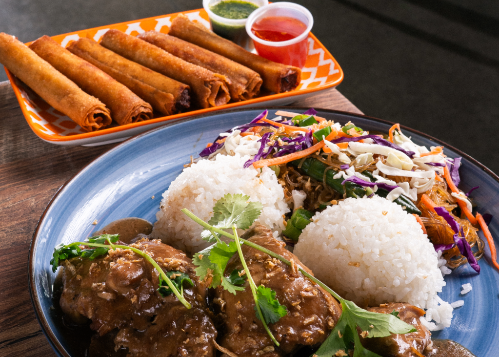 A rice dish with a fried rolled appetizer behind it