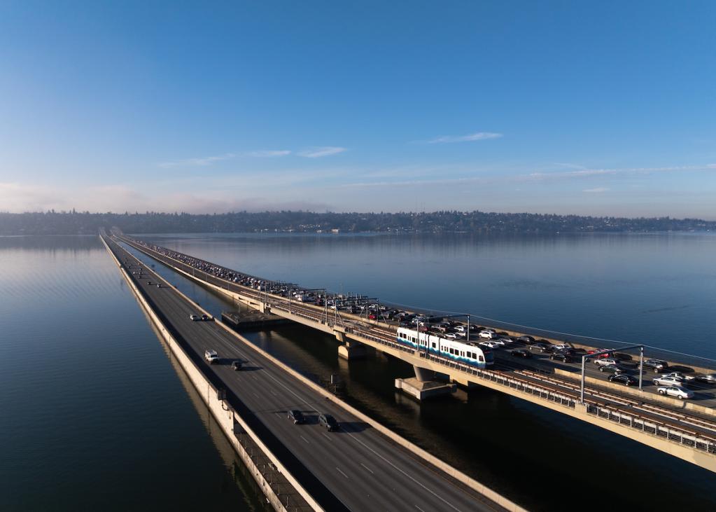 A drone photograph of a link light rail vehicle riding on the floating bridge