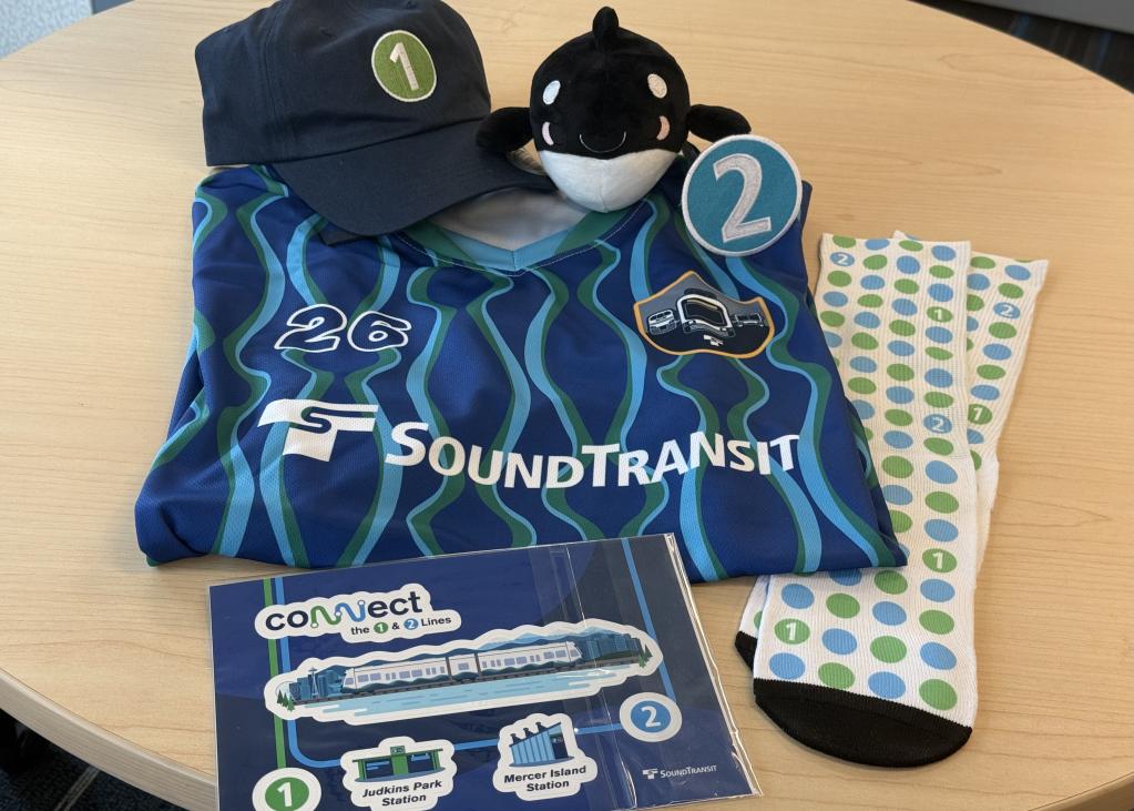 A jersey, hat, sticker pack, socks, and a Boop plushie on a table