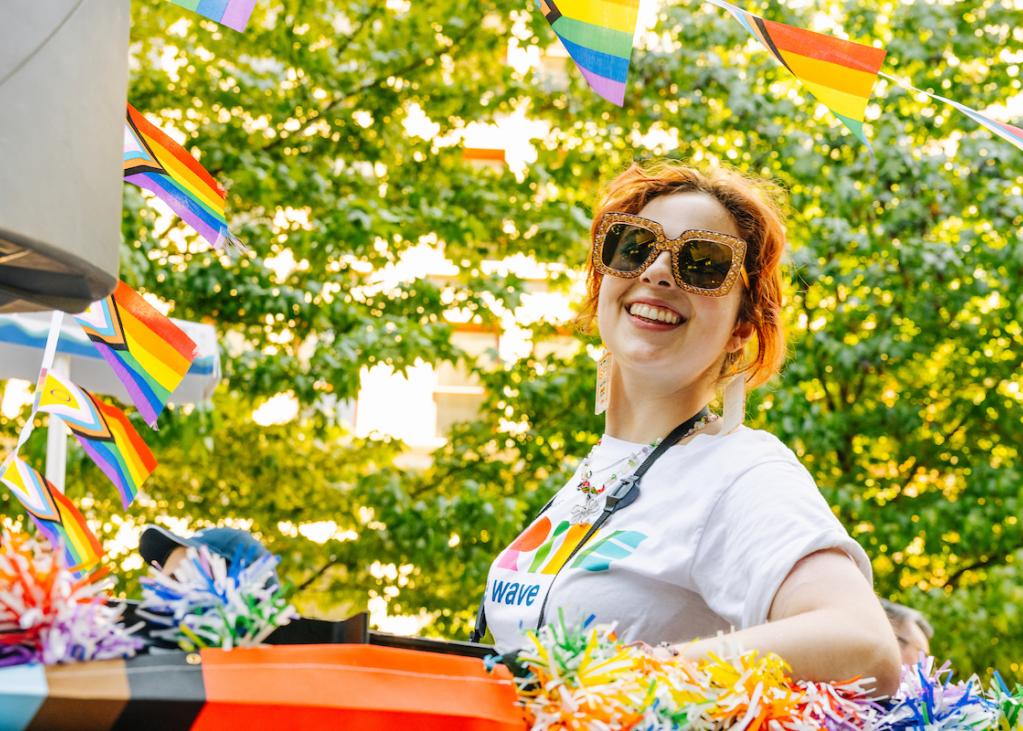 A Sound Transit employee rides in a Pride Parade float on a sunny day
