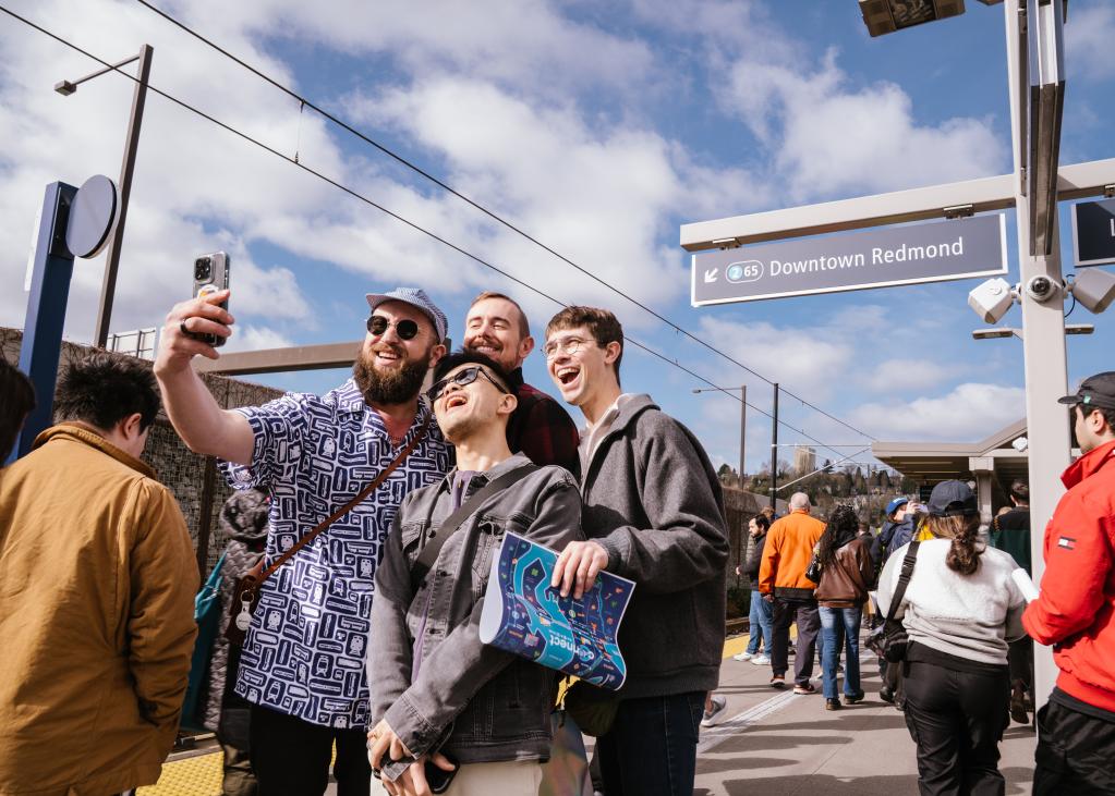A group of friends take a photo on the Judkins Park Station platform on a sunny day