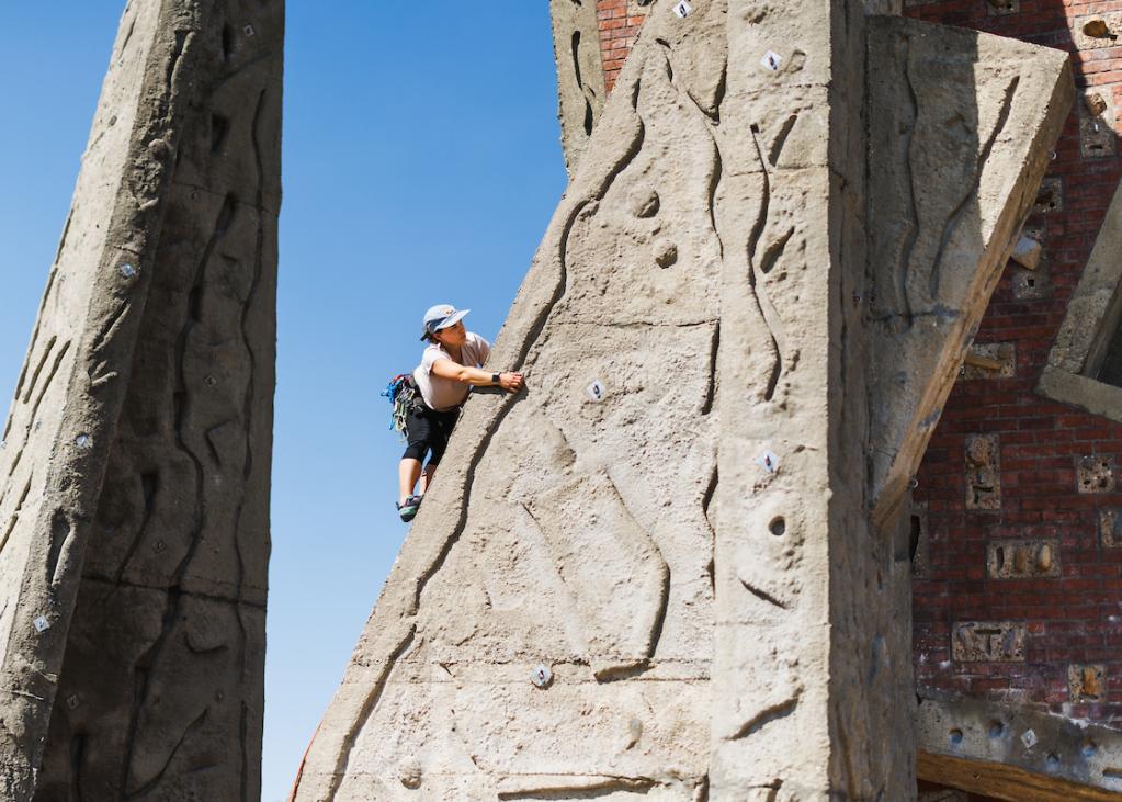 A person perches on the climbing rock at Marymoor Park on a sunny day