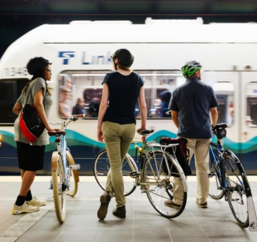 Three people stand with their bikes at a Link light rail station.