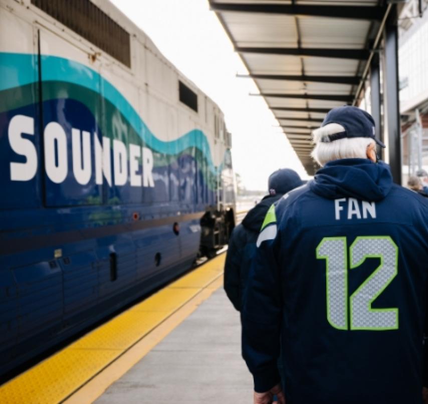 Seahawks fans gather on a Sounder train platform.